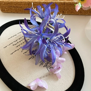 Détail d'une pince à cheveux en tissu avec fleur de lys et pampilles de perles