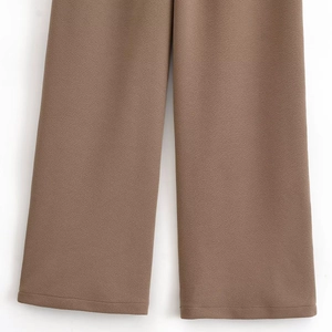 Close-up of brown crepe fabric texture and double-stitched hem on fashion trousers
