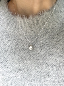Close-up of minimalist silver pearl pendant on a sleek snake chain necklace