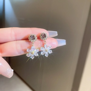 Macro shot of sparkling flower drop earrings with purple stone and clear zircon petals