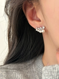 Macro view of elegant curved silver earrings with sparkling zircon and graduated pearls