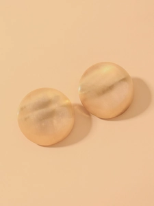 Detailed close-up of golden spherical stud earrings with brushed metallic texture detail