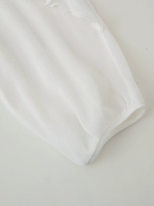 Close-up of white mesh fabric showing breathable texture and clean cuff stitching detail