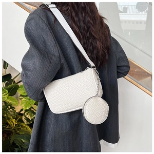 Close-up of a white woven shoulder bag with a round coin purse on a fashion model