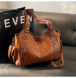 Detail of vintage caramel tote bag with litchi grain texture and metal zipper accents