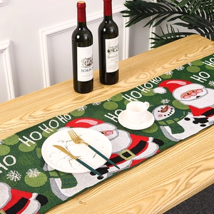 Macro detail of green knitted Christmas table runner with HO HO HO embroidery on wood table