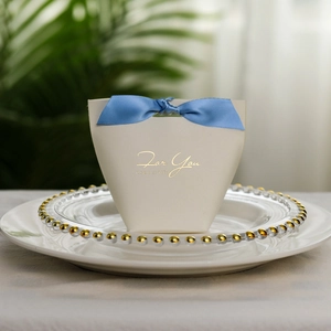 Detail of beige trapezoidal gift box with blue ribbon and gold For You engraving