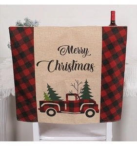 Detailansicht der Merry Christmas Stuhlhusse aus Jute mit rotem Karo-LKW und Bäumen.