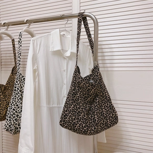 Dettaglio di borse tote in tela leopardata appese in un armadio dal design minimalista