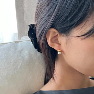 Close-up of minimalist gold curved earrings with white pearl detail on female ear