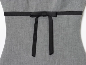 Detail of grey satin dress featuring a contrasting black ribbon waist tie with a bow