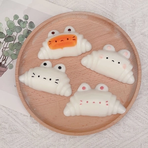 Detail of four cartoon croissant cat figurines on a wooden tray with lace background