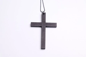 Detail of dark brown wooden cross necklace with black bead chain on white background