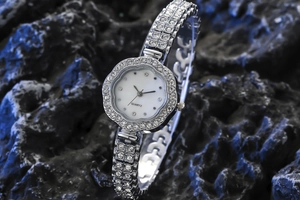Détail d'une montre femme en forme de fleur argentée avec cristaux sur pierre