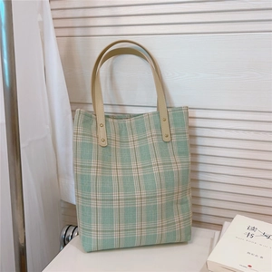 Détail du sac cabas en toile à carreaux verts et blancs avec anses en cuir beige