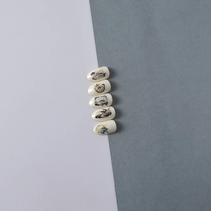 Detail of 5D ink bamboo nail stickers with gold foil and bird motifs on cream base
