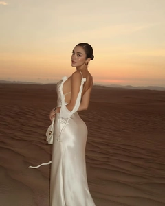 Detail of white backless satin dress showing floral shoulder accents and flowing ribbons
