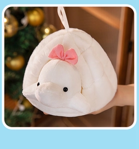 Close-up of white plush turtle hand warmer with pink bow in a warm festive setting