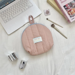Detailed flat lay of a pink quilted shell makeup bag with blue zipper and handle