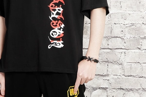 Detail of nautical anchor leather bracelet worn with casual black printed tee shirt
