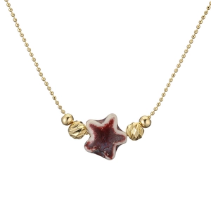 Detail showing a star-shaped ceramic pendant with red and white glaze on a golden chain