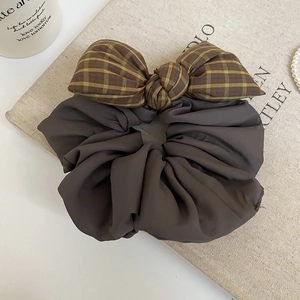Detailed view of dark grey fabric scrunchie with a vintage plaid bow on a beige surface