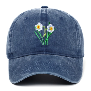 Close-up of white narcissus flower embroidery on washed navy blue denim baseball cap