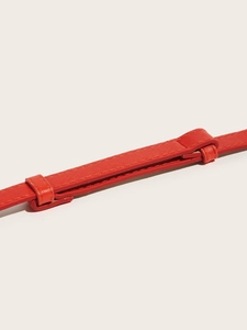 Detail of red synthetic leather belt featuring cross-grain texture and matching stitching