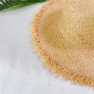 Détail d'un chapeau de paille avec texture tissée et bordure à franges pour la plage