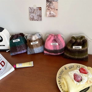 Close-up of four colorful plaid woolen drawstring storage pouches on a wooden table