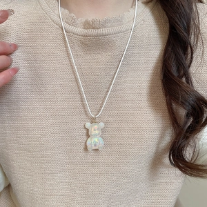 Close-up of a model wearing a creative iridescent resin bear pendant with a white cord necklace