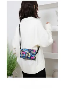 Detail shot of blue floral oxford fabric crossbody bag with black sport logo and strap