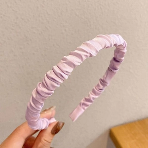 Close-up of lavender pleated satin headband showing rich fabric texture and silk sheen