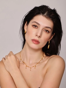 Detail of gold water drop earrings and pearl pendant necklace set on female model