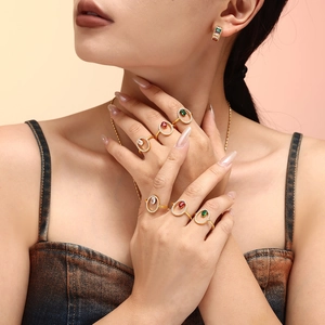 Luxurious geometric gold plated rings with vibrant red, green and clear gemstones on model