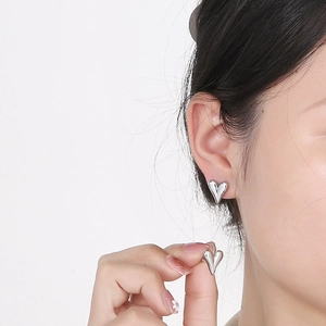 Close-up of minimalist heart stud earring in polished silver worn by a model