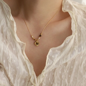 French vintage gold necklace with brown tiger eye stone and pearls worn by a model