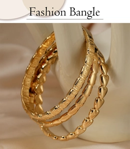 Detailed view of a 3-piece gold stainless steel bangle set with heart and textured patterns