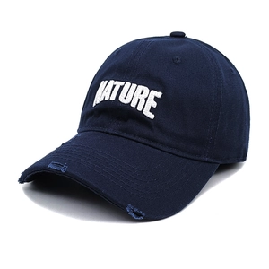 Close-up of embroidered NATURE logo and vintage distressed details on dark blue baseball cap