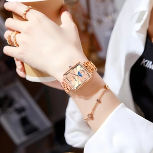 Detail view of a luxury square rose gold watch with sun-moon display on a female wrist