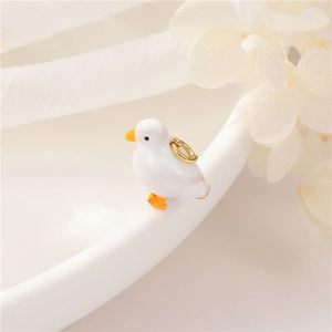 Detail shot of a cute white duck pendant with orange beak and golden metal loop