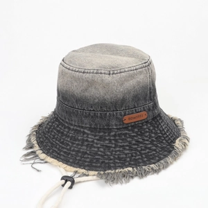Detail of frayed denim sun hat with vintage brown leather logo and windproof drawcord
