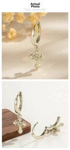 Close-up of gold cross hoop earrings with white zircon stone inlay and retro texture