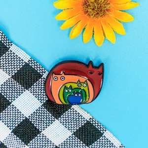 Colorful rainbow cat enamel brooch with Russian nesting doll design on blue background