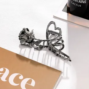 Detail of dark gunmetal rose and heart-shaped metal hair claw clip with mirror finish