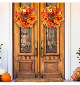 Close-up of autumn harvest wreaths with pumpkins and maple leaves on wooden doors