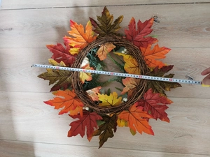 Top view of large autumn wreath with maple leaves and pumpkins on wooden floor measuring 60cm
