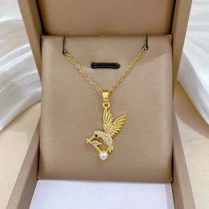 Détail du pendentif colibri doré avec perle et cristaux brillants sur de la soie