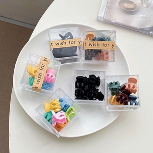 Gros plan de mini pinces à cheveux colorées en plastique dans une boîte sur un plat blanc