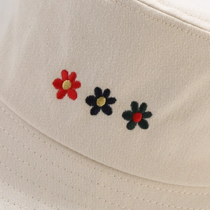 Close-up of three small flower embroideries on a beige cotton bucket hat fabric